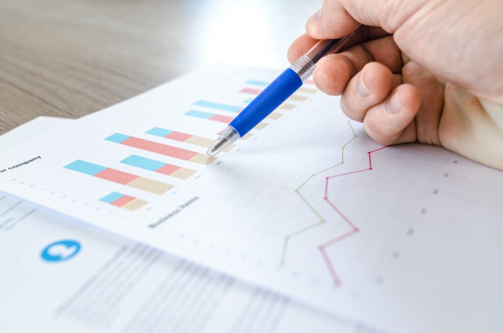 A close up of a hand holding a pen pointing at figures on a chart.