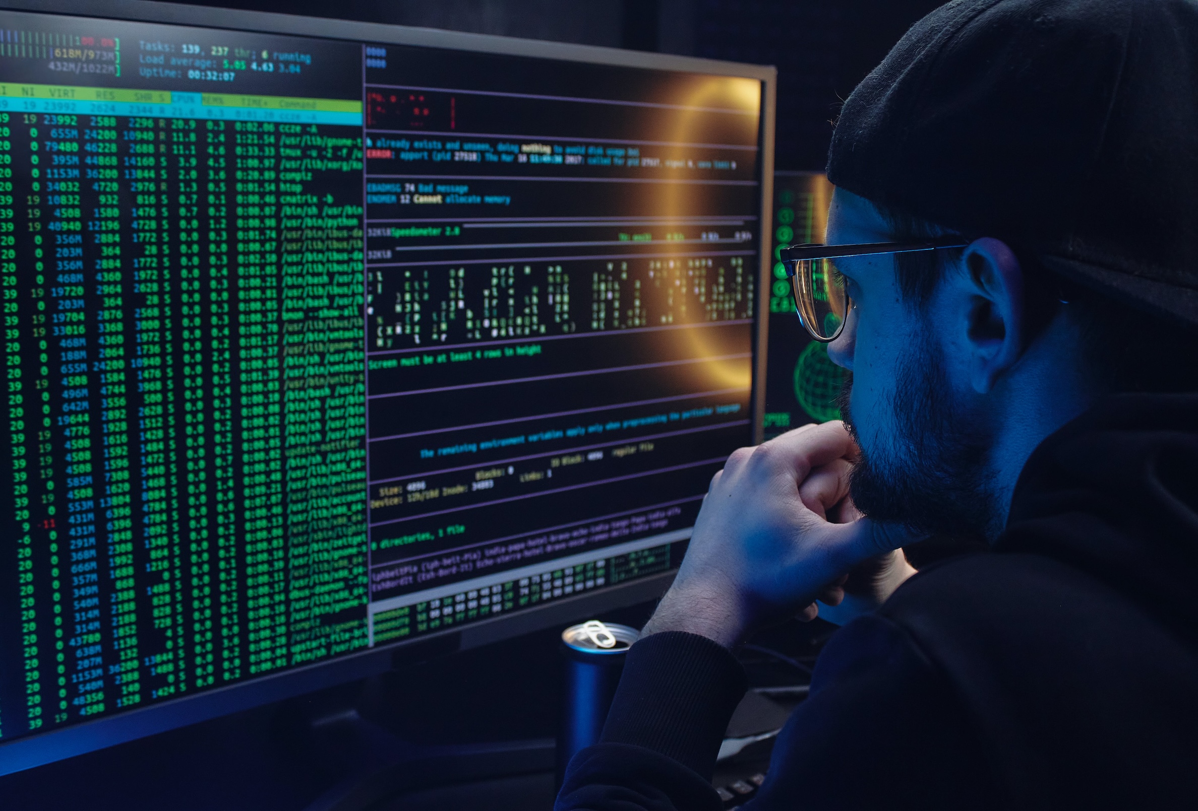 A middle aged male business professional with glasses looking at a computer screen that. is showing lines of code