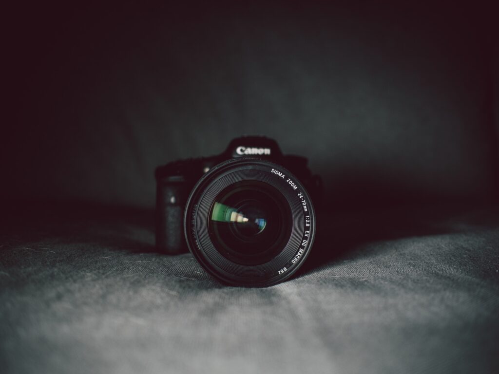 A close-up of a Canon camera against a grey background.