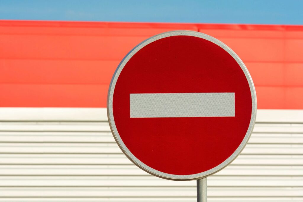 A do not enter road sign in front of a silver and red building 