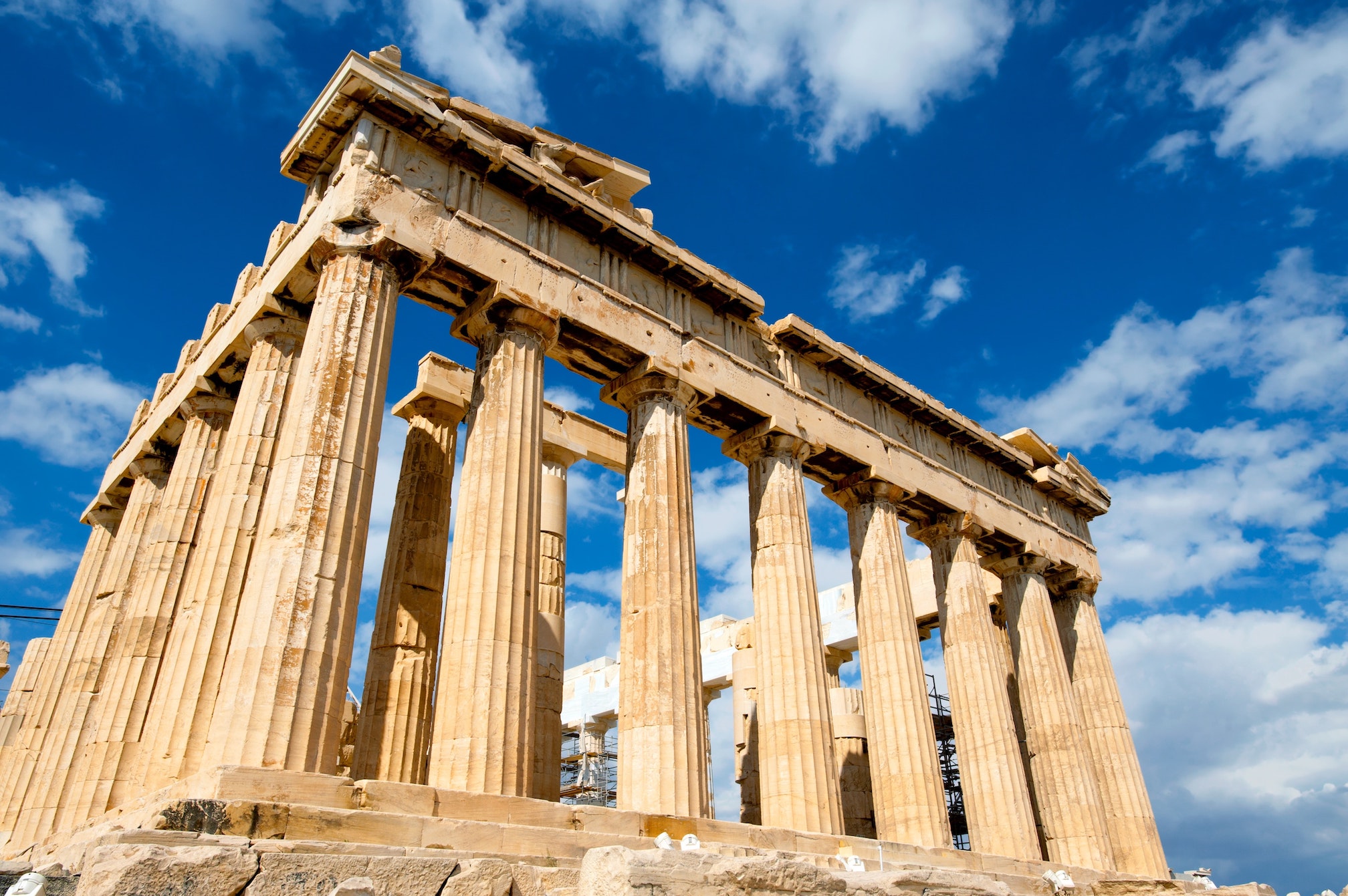 Pillars of a roman temple against a blue sky with small white clouds