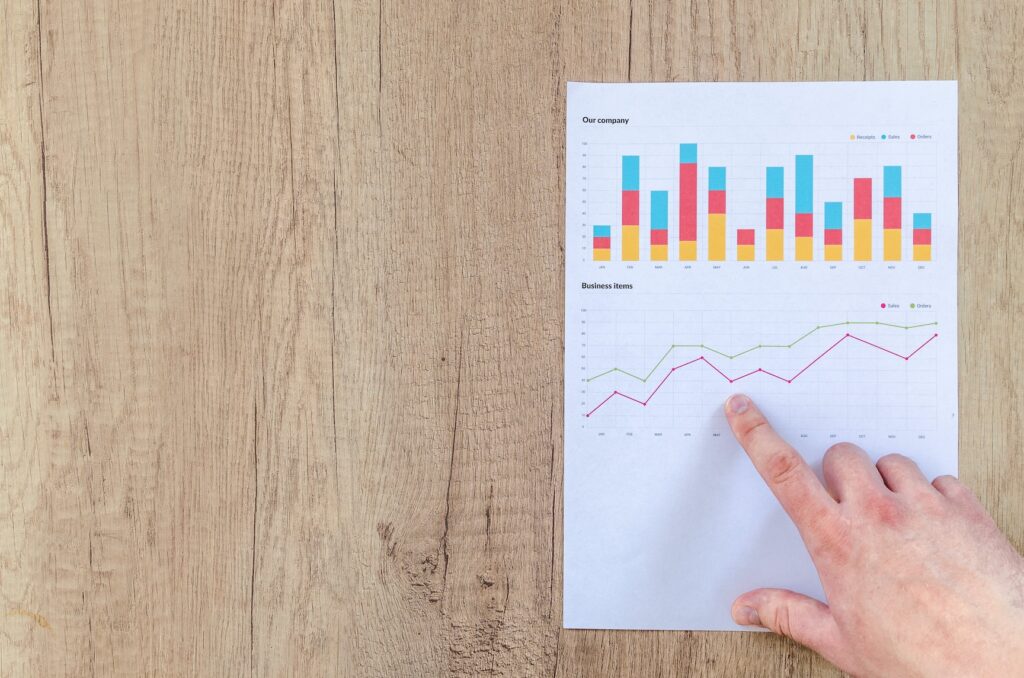 A single right hand pointing towards a chart on a sheet of white paper showing a graph in which the values are improving 