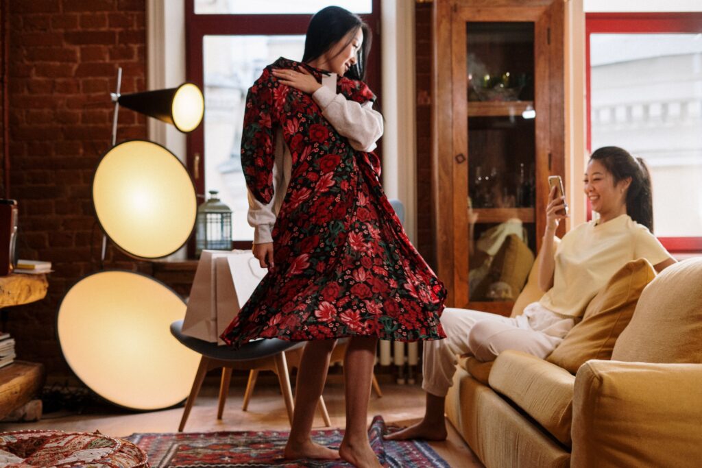 A young dark haired woman showing a ling red flowery dress to another young dark haired woman