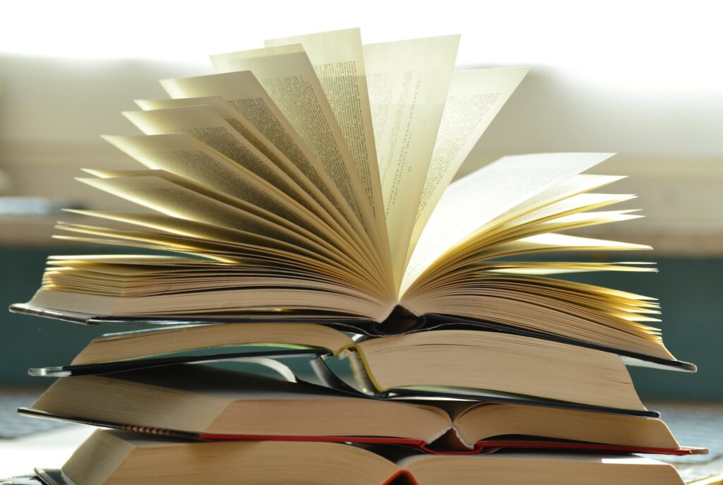 A table piled with open hardback books 