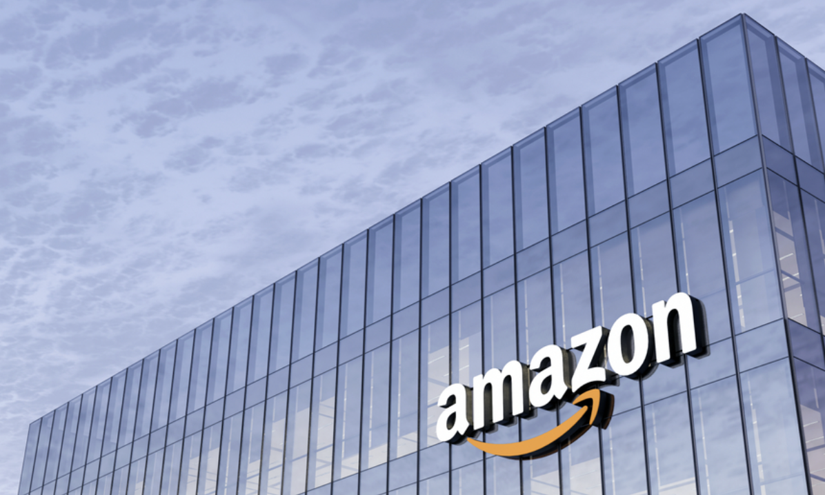 A glass Amazon building reflecting a cloudy sky that surrounds the building and serves as a backdrop